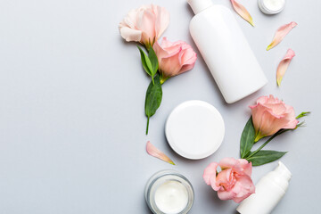 Composition with cosmetic products and beautiful roses on color background. Copy space, flat lay