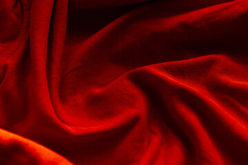 Close-up of luxurious red velvet fabric, draped and folded, showcasing its rich texture, deep color, and soft, flowing curves.
