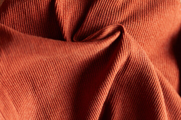 Close-up of textured fabric with linear patterns and warm, earthy tones, showcasing folds and surface details.