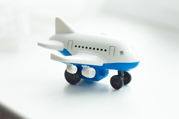 Toy airplane: A miniature, mostly white plane with blue trim and black wheels, ready for playtime adventures. Small enough to fit in your palm.