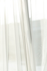 Obraz premium Sheer white curtains filter sunlight, creating a soft, serene atmosphere. Light fabrics add an airy touch to interior design.