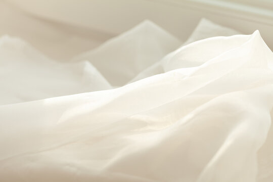 Soft, flowing fabric illuminated by gentle sunlight. Its delicate texture and pale color create a serene atmosphere.