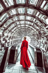 Naklejka premium Woman in red coat walking through futuristic tunnel