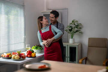 A man and a woman are hugging in a kitchen