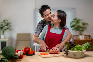A man and woman are in a kitchen cutting vegetables