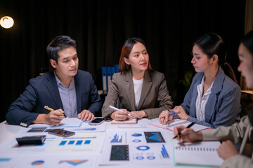 A group of people are sitting around a table with papers and pens