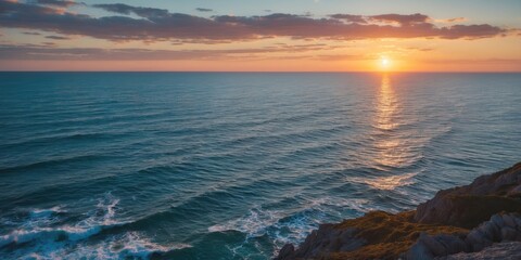 Obraz premium Sunset over calm ocean waves with rocky coastline and evening sky reflections at horizon in tranquil natural landscape scene