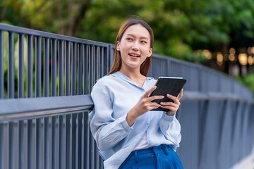 Fototapeta premium Asian Businesswoman Using Tablet In Front of A Modern Office Building In the Financial District