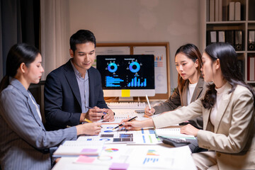Four people are sitting at a table with a computer monitor in front of them