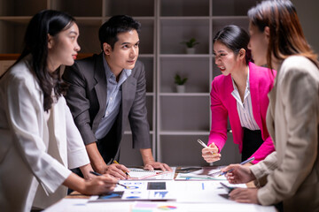 Four people are sitting around a table with papers and a deck of cards