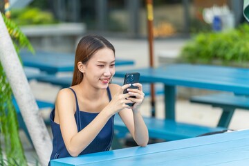 Fototapeta premium Young Asian Woman Using Phone Outdoors