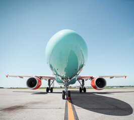 Turquoise airplane with red engines at the airport. Nose of turquoise aircraft - low angle view on...