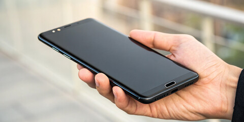 A Hand Holding a Black Smartphone with a Blank Screen, Indicating Potential for Customization