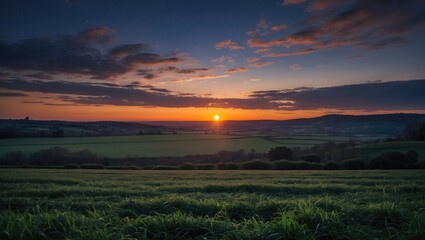 Fototapeta premium Sunset over green fields with rolling hills and scattered clouds in the sky during twilight hours. Scenic rural landscape at dusk.