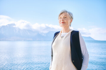 Fototapeta premium Outdoor portrait of beautiful 55 - 60 year old woman enjoying nice sunny day by the lakeside, image taken in Montreux, Switzerland