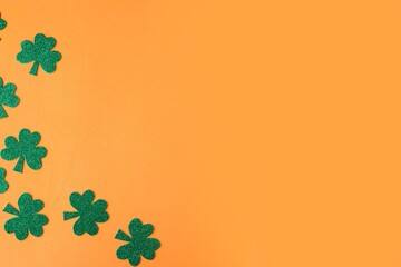 St. Patrick's Day side border paper shamrocks on orange background. Copy space for the text