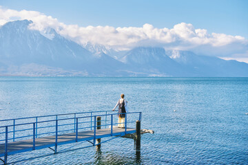 Naklejka premium Nature background of lake Geneva and swiss Alps, woman admiring winter landscape, image taken in Montreux, Switzerland