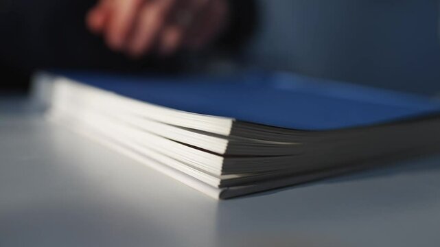 A book is opened to a page with a hand on it. The book is blue and white