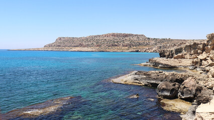 Coastal landscape featuring crystal-clear azure waters and rugged rocky shores. For travel, tourism, seaside relaxation, and nature harmony concepts.