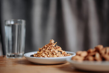 A healthy breakfast scene with granola in a white plate, a glass of water, and a wooden table, perfect for promoting nutrition, wellness, and morning routines.