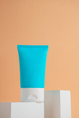 Plastic white tube for cream or lotion. Skin care or sunscreen cosmetic with stylish props on cream background.