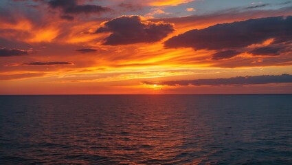 Obraz premium Vibrant sunset over the ocean with dramatic clouds reflecting orange and yellow hues in the sky and calm waters below