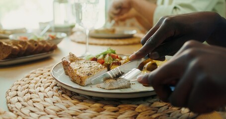 A man uses cutlery while having dinner with friends, a close-up of his hands, no face