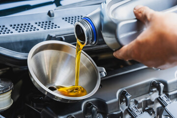 Close up car mechanic pouring engine oil into container during car maintenance in repair shop