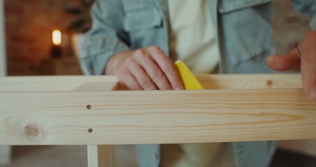 A man polish a rack with sandpaper in a stylish home interior, close-up of his hands, no face
