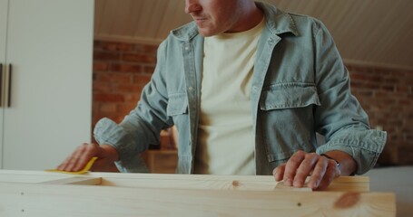 A man polish a rack with sandpaper in a stylish home interior