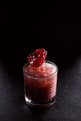 Red cocktail with ice in an old fashioned glass. A piece of pomegranate decorates the refreshing drink. Long alcoholic drink for a bar cocktail card. Party concept for girls.