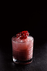 Red cocktail with ice in an old fashioned glass. A piece of pomegranate decorates the refreshing drink. Long alcoholic drink for a bar cocktail card. Party concept for girls.