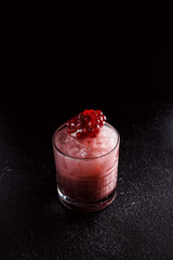 Red cocktail with ice in an old fashioned glass. A piece of pomegranate decorates the refreshing drink. Long alcoholic drink for a bar cocktail card. Party concept for girls.