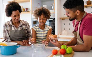 Overjoyed young african american family with kid have fun cooking at home together,