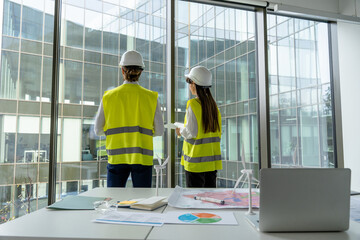 Two engineers in yellow vests standing at the panoramic window
