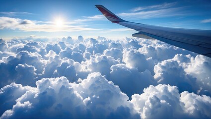 Fototapeta premium Airplane Wing Over Soft White Clouds with Bright Sunlight and Clear Blue Sky Ideal for Travel and Adventure Themes