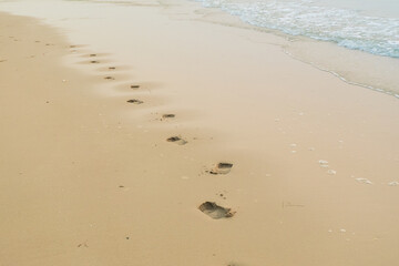 Footprints of human feet on the sand near the water on the beach.