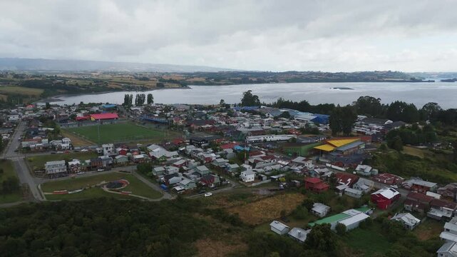Aerial view of Chonchi, a Chilean town and commune located in Los Lagos Region, showing buildings, Huillinco lake and soccer field