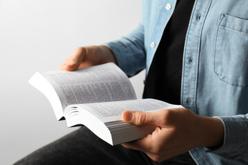 Man reading Holy Bible in English language on light background, closeup