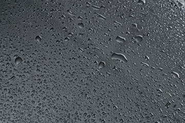 Water drops on dark grey glass surface, top view
