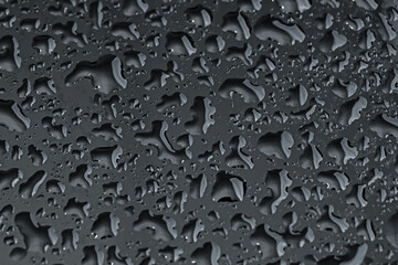 Water drops on black glass surface, closeup