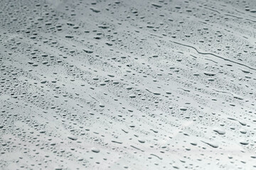 Water drops on grey glass surface, closeup
