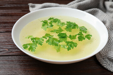 Tasty chicken bouillon in bowl on wooden table, closeup