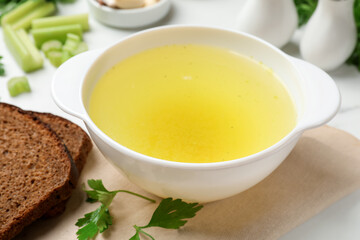 Tasty chicken bouillon in bowl served on white table, closeup