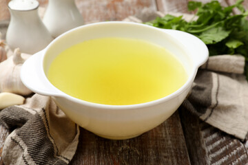 Tasty chicken bouillon in bowl on wooden table, closeup