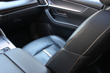 Fototapeta premium The passenger seat inside the car is covered in expensive leather with perforations for cooling and heating. Leather trimming and car interior upholstery 