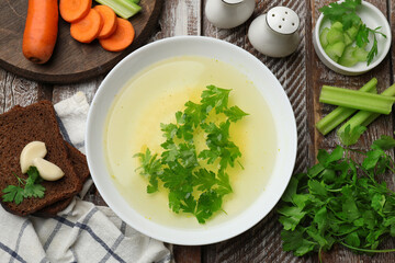 Tasty chicken bouillon served on wooden table, flat lay