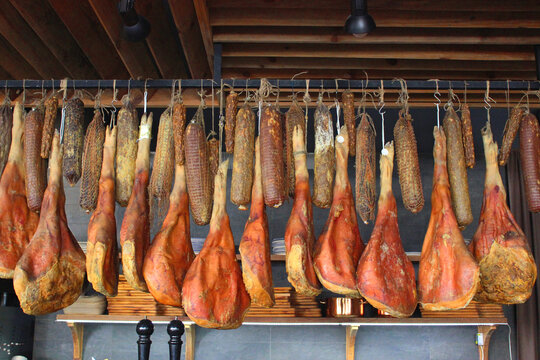 Dry cured meat products and whole serrano hams hang on a ceiling rack. Spanish ham an important part of Spanish cuisine 
