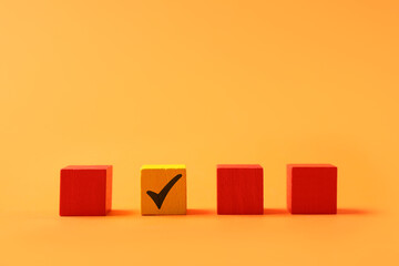 One color cube with check mark among others on orange background
