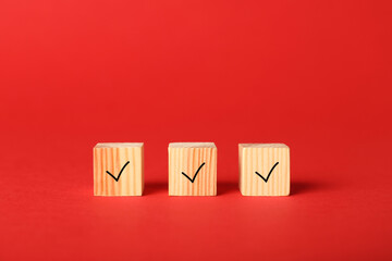 Wooden cubes with check marks on red background